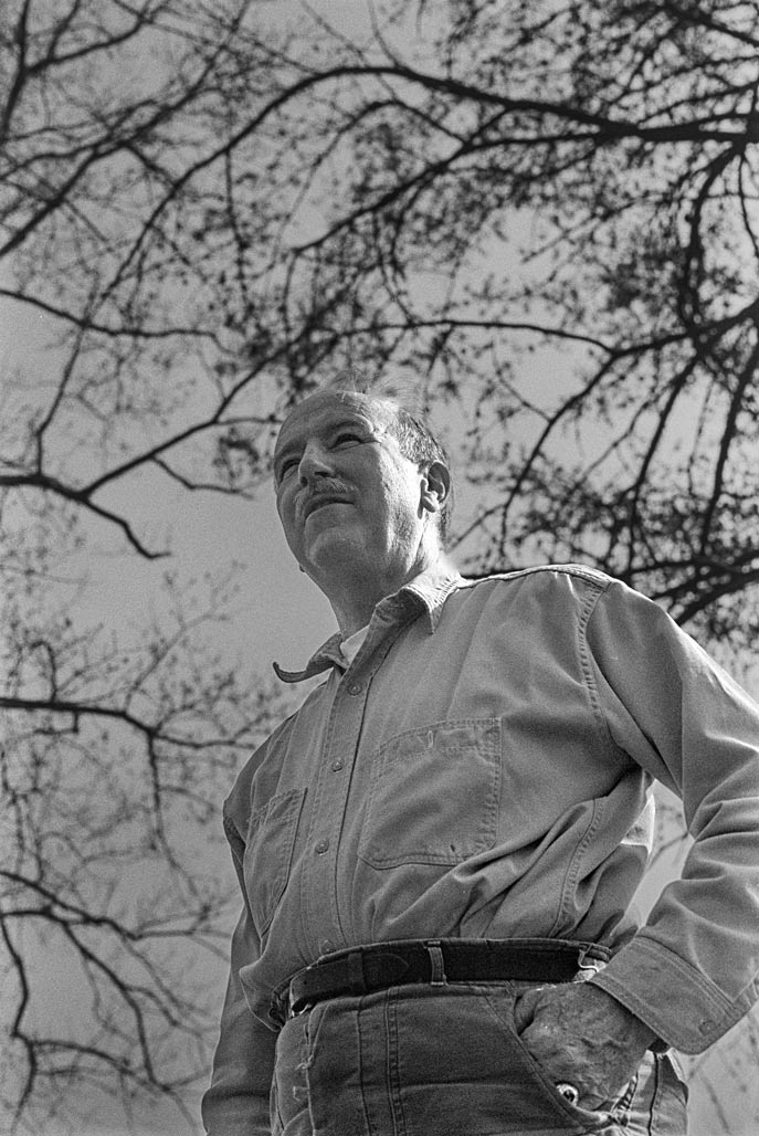 man standing winter branches, sky.